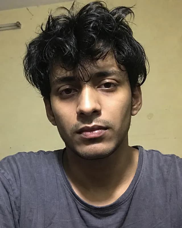 Before: the AI sample person in a plain selfie, messy hair, grey t-shirt, flat light in a bare room